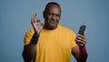 Mature african athletic man stands in studio gray background looking phone screen sportive male athlete trainer browsing