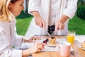 Mature appealing woman tasting warm pancakes with some honey for breakfast