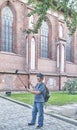 Mature Asian blogger shooting video for his blog on social network near wall of Cathedral, Kaliningrad, Russia Royalty Free Stock Photo