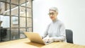 Mature asian business woman wears glasses using laptop computer sit at workplace desk Royalty Free Stock Photo