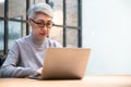 Mature asian business woman wears glasses using laptop computer sit at workplace desk Royalty Free Stock Photo