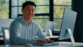Mature Asian businessman chinese korean office worker specialist male work on computer develop project online look at