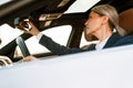 Mature asian businesswoman looking in rear-view mirror while driving car Royalty Free Stock Photo