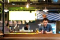 Mature asian chinese man with tired and thoughful face sitting at counter bar, pub or restaurant drinking beer looking at smartpho