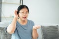 Mature Asian deaf disabled woman having hearing problems holds his hand over the ear, listens carefully, hard of hearing