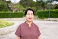 Mature asian woman standing at public park in the morning,Happy and smiling,Senior care insurance concept
