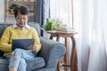 Mature Asian Woman Using Digital Tablet Sitting At Home