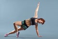 Mature athletic redhead woman doing fitness exercises, gray studio background