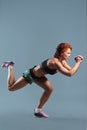 Mature athletic redhead woman in sportswear t-shirt and shorts doing fitness exercises