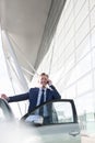 Mature attractive businessman smiling while talking on smartphone outside the car in airport Royalty Free Stock Photo