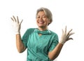 Mature attractive and happy medicine doctor woman or hospital nurse in medical scrubs in face mask playful showing hands in latex Royalty Free Stock Photo