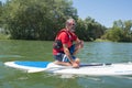Mature attractive rider contemplating nature sitting on paddle board
