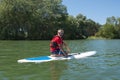 Mature attractive rider contemplating nature sitting on paddle board