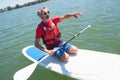 Mature attractive rider contemplating nature sitting on paddle board