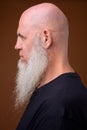 Mature bald man with long gray beard against brown background Royalty Free Stock Photo