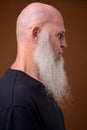 Mature bald man with long gray beard against brown background Royalty Free Stock Photo