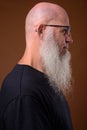 Mature bald man with long gray beard against brown background Royalty Free Stock Photo