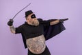 Fat man in Zorro costume with bare abdomen stands in bellicose pose on purple background