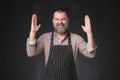 Mature bearded man in apron bragging about the big size of something.