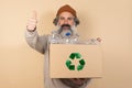 Mature, bearded man holding a cardboard box with plastic bottles and a recycling sign on it Royalty Free Stock Photo