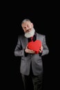 Mature bearded man wear suit holds red heart shaped gift box, isolated black background Royalty Free Stock Photo