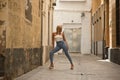 Mature, beautiful, blonde woman in white top and jeans, posing in funny attitude on a lonely city street. Concept beauty, fashion