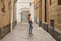 Mature, beautiful, blonde woman in white top and jeans, posing in funny attitude on a lonely city street. Concept beauty, fashion