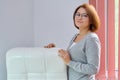 Mature beautiful business woman near office leather white armchair Royalty Free Stock Photo