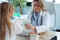 Mature beautiful female doctor measuring heart and blood pressure while taking care to young patient in the medical consultation Royalty Free Stock Photo