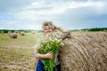 Mature beautiful woman with a bouquet of wild flowers on a mown wheat field. Active recreation, perfect maturity Royalty Free Stock Photo