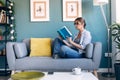 Mature beautiful woman reading a book sitting on couch at home Royalty Free Stock Photo