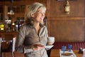 Mature beautiful woman in restaurant with cup of coffee Royalty Free Stock Photo