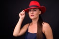 Mature beautiful woman wearing red fedora hat against black background Royalty Free Stock Photo