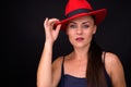 Mature beautiful woman wearing red fedora hat against black background Royalty Free Stock Photo