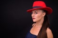 Mature beautiful woman wearing red fedora hat against black background Royalty Free Stock Photo