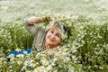 Mature beautiful woman with a wreath and a bouquet of wild flowers in a large field of daisies. Active recreation, perfect Royalty Free Stock Photo