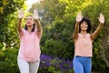 Mature biracial woman and young biracial woman practicing yoga outdoors, at home