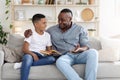 Mature Black Father And His Preteen Son Reading Book At Home Together Royalty Free Stock Photo