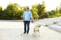 Mature blind person with white walking cane and guide dog near stairs