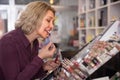 Mature blond woman choosing lip plumper on display Royalty Free Stock Photo