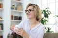 Mature blond woman in couch having a tea or coffee Royalty Free Stock Photo