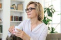 Mature blond woman in couch having a tea or coffee Royalty Free Stock Photo