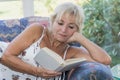 Mature blond woman is reading book on the couch Royalty Free Stock Photo