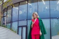 mature blonde curly woman in suit walks in business district and uses her phone. Royalty Free Stock Photo