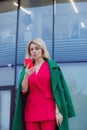 mature blonde curly woman in suit walks in business district and uses her phone. Royalty Free Stock Photo