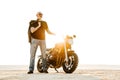 Mature bold man with tattoo looking at camera while posing by motorbike Royalty Free Stock Photo