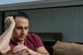 Mature Brazilian man 44 years old sitting on the brown sofa, behind the glass, sad and crestfallen.