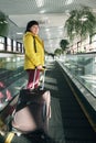 Mature brunette woman at the airport stands on a moving walkway