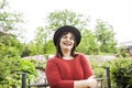 Mature brunette woman in green garden wearing hat, smiling, friendly welkoming, lifestyle people concept close up Royalty Free Stock Photo