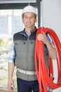 mature builder holding red flexible pipe